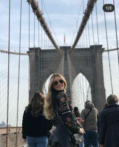 a woman standing in front of the brooklyn bridge