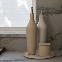 two white vases sitting on top of a marble counter