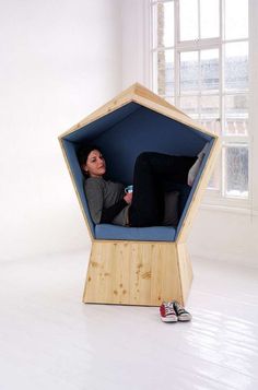 a woman is sitting in a chair made out of plywood and blue fabric, with her feet on the floor