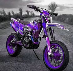 a purple dirt bike parked on the side of a road