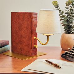 a desk with a lamp, book and pen on it