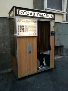 a man is sitting in a small booth on the street