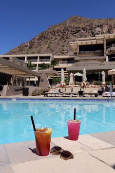 two drinks sitting on the edge of a swimming pool