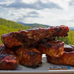 several pieces of meat sitting on top of a white plate with mountains in the background