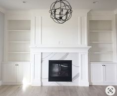 an empty living room with white bookcases and a black chandelier hanging from the ceiling