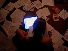 a woman is sitting on the floor with papers all over her and looking at a laptop