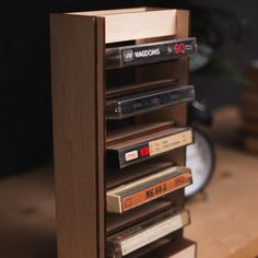 a stack of cassettes sitting on top of a wooden table next to a clock