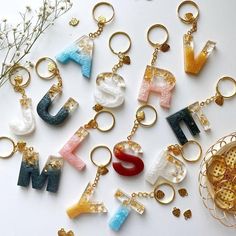 the letters are made out of different types of beads and gold chains, along with other keychains