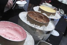 there are many different types of ice creams in buckets on the table together