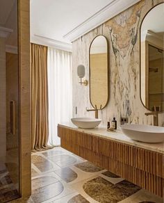 a bathroom with two sinks and large mirrors on the wall next to eachother