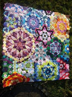 a quilt is laying on the ground with many different colors and shapes, including an eight pointed star