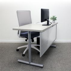 an office desk with a computer on it and a potted plant in the corner