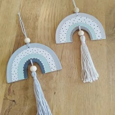 two wooden rainbows with tassels hanging from them on a wood table top