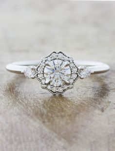 a diamond engagement ring with three stones on the band and an old - fashioned setting