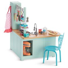 a toy kitchen with a blue chair and table in front of the counter top on wheels