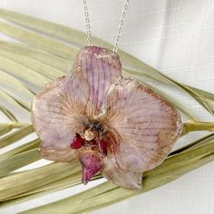 a pink flower is hanging from a silver chain