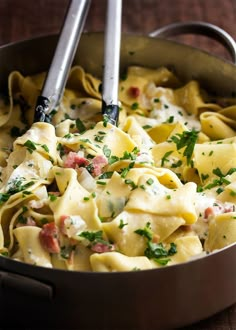 a pan filled with pasta and meat on top of a wooden table