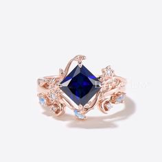 a ring with a blue stone surrounded by white stones and leaves on the sides, set in