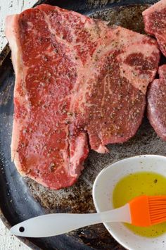 raw meat being marinated in oil and seasoning on a plate with an orange spatula