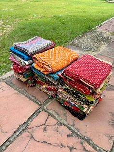 a pile of colorful cloths sitting on top of a stone walkway in front of a grassy field