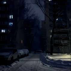 cars parked on the side of a snow covered road at night with buildings in the background