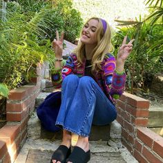 a woman sitting on steps making the peace sign