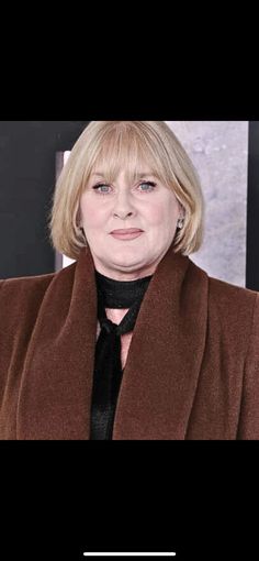 a woman with blonde hair wearing a brown coat