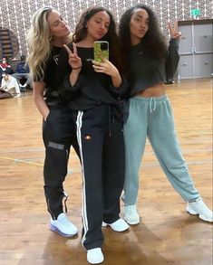 three young women taking a selfie with their cell phones in an indoor gym area