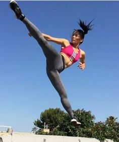 a woman is doing a kick flip in the air with her legs spread out and one leg up