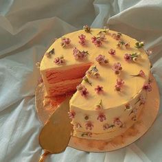 a white cake with pink flowers on it and a slice missing from the cake that has been cut