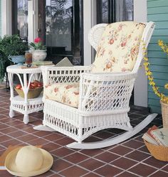 a white rocking chair sitting on top of a porch next to a table with fruit