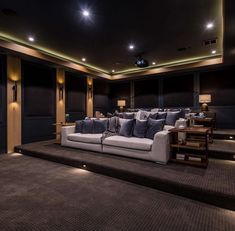 a home theater with couches and tables in the middle of an area that is lit up by recessed lighting