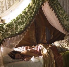 a woman laying in bed under a canopy