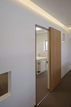 an open door leading into a room with white walls and brown carpeted flooring