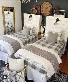 two twin beds in a bedroom with white and black bedding, mirror on the wall