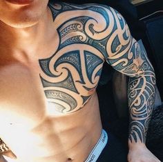 a man with tattoos on his chest sitting in a car