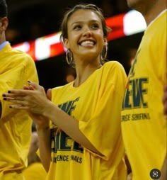 a woman in a yellow shirt standing next to two other people on a basketball court