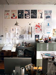 an office filled with lots of clutter and posters on the wall above it's desk