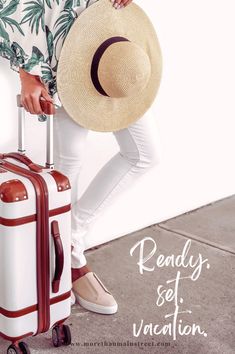 a woman with a hat and suitcase is posing for the camera while holding her luggage