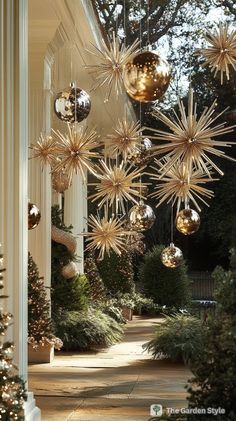 christmas decorations hanging from the side of a white house with gold balls and stars on it