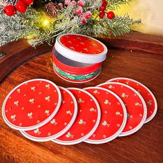 six red plates sitting on top of a wooden table next to a christmas tree and tinsel