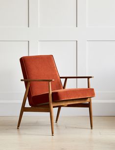 an orange chair sitting on top of a hard wood floor next to a white wall