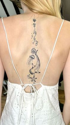 the back of a woman's white dress with fish tattoos on her upper back