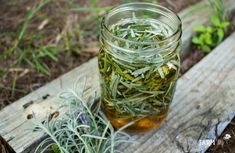 a glass jar filled with green tea sitting on top of a wooden table next to plants