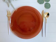 an orange plate with silverware and leaves on it