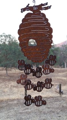 a metal beehive hanging in the middle of a field