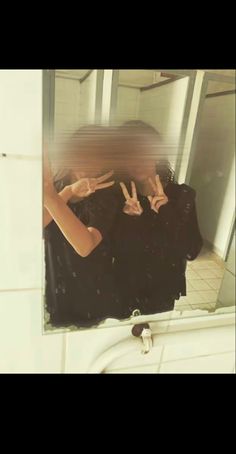 a woman taking a selfie in front of a bathroom mirror with her hands up