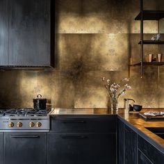 a kitchen with black cabinets and gold backsplash