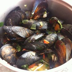 a bowl full of mussels and vegetables in broth