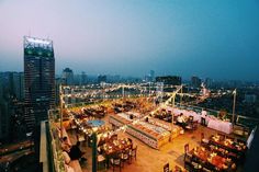 an outdoor dining area on top of a building in the middle of city at night